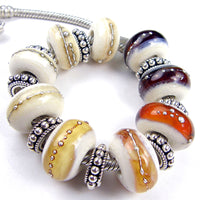 Example showing various shades of amber brown and ivory large hole lampwork beads wrapped in fine silver 