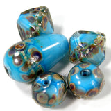 Example of variety of styles of dark sky blue raku silver encased handmade lampwork glass diamond beads